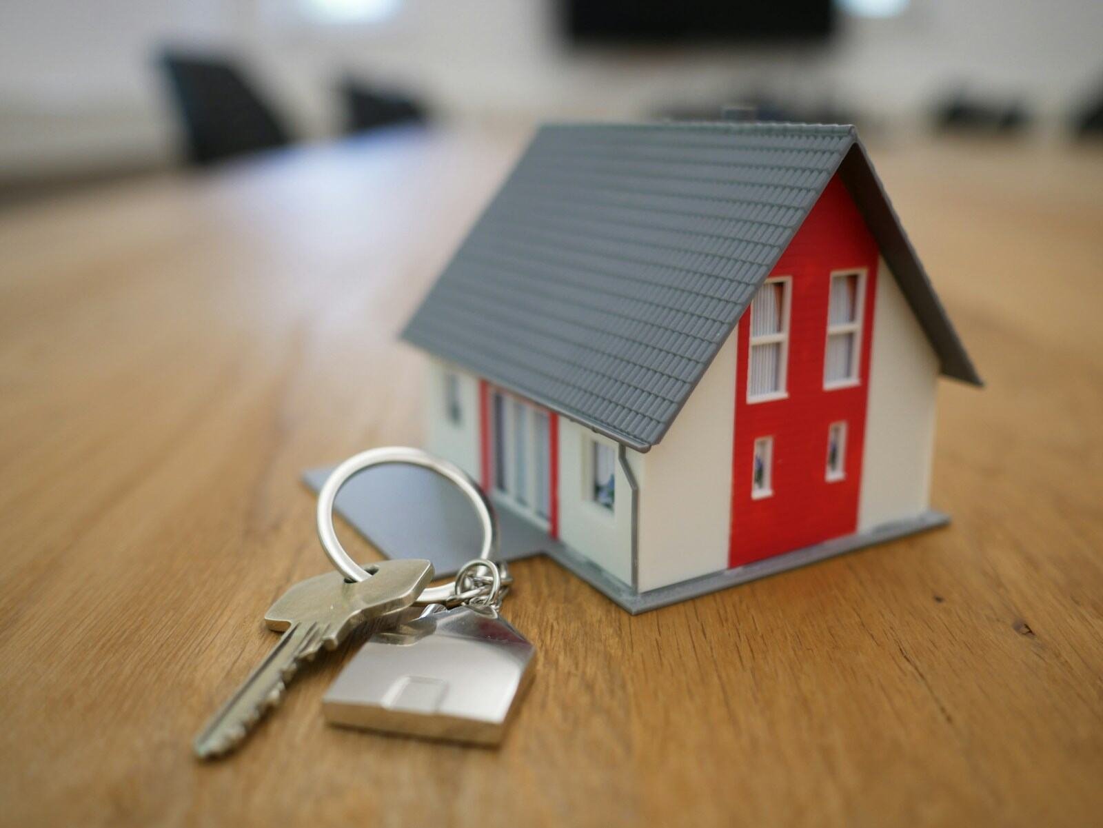 A small model house with a set of keys on a table
